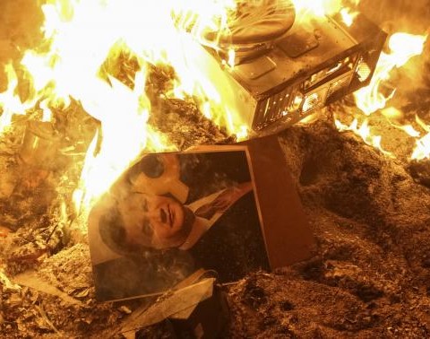 A portrait of Ukrainian President Viktor Yanukovich burns near the destroyed building of  the security service in Lviv