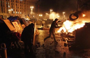 An anti-government protester throws a tire during clashes with riot police at the Independence Square in Kiev
